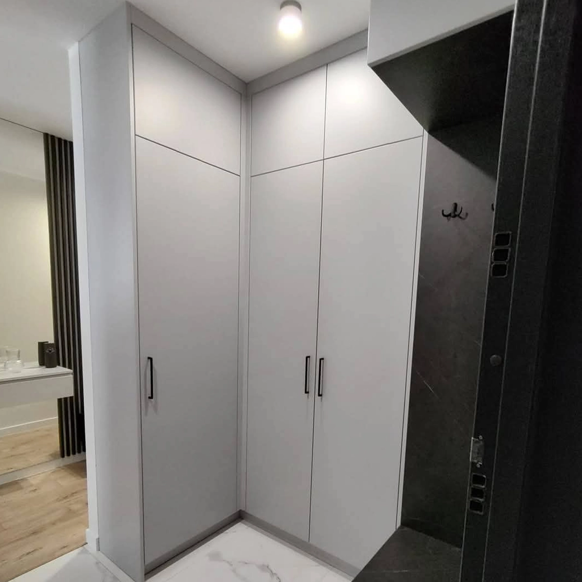 Deckenhoher Einbauschrank nach Maß in Grau mit schwarzen Griffen, durchgehend bis zur Decke gebaut — gefertigt von MAGUBO.