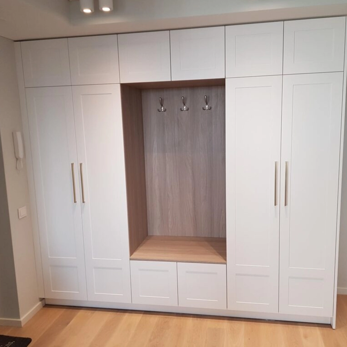 Schrank nach Maß mit Kassettenfronten und Garderobenpaneel in Holzoptik, passgenau in die Wandnische eingebaut — gefertigt von MAGUBO.